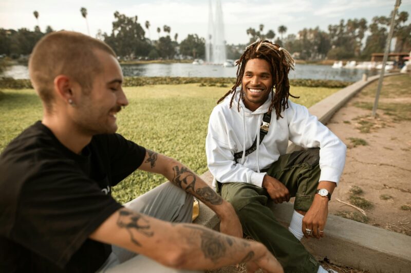Two men sitting and smiling by a pond