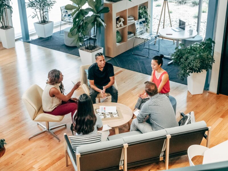 A group of five sitting around a coffee table in a bright office space